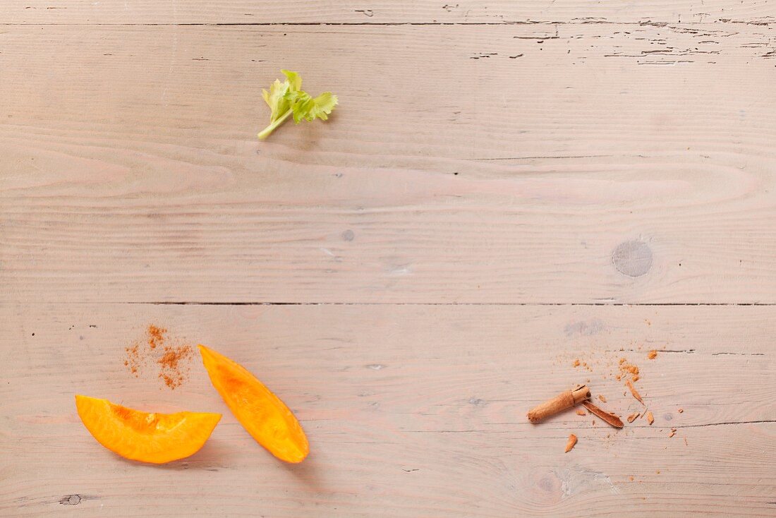 Pumpkin wedges and cinnamon on a wooden surface