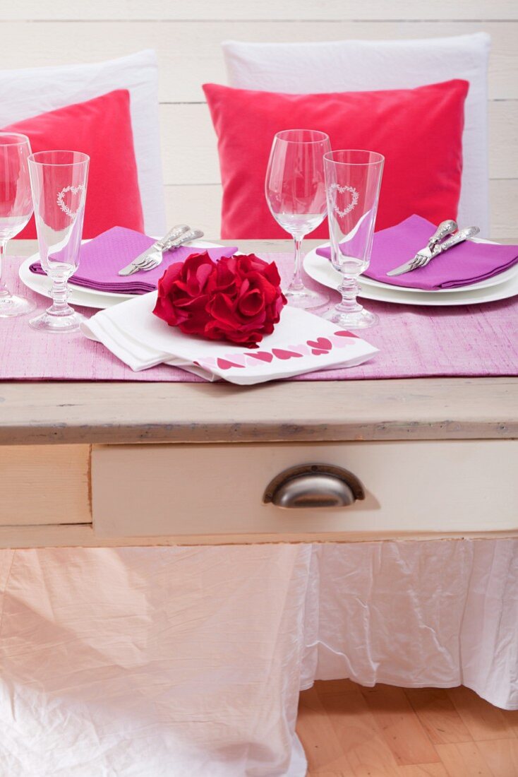 Festliche gedeckter Tisch mit herzförmig arrangierten Rosenblättern