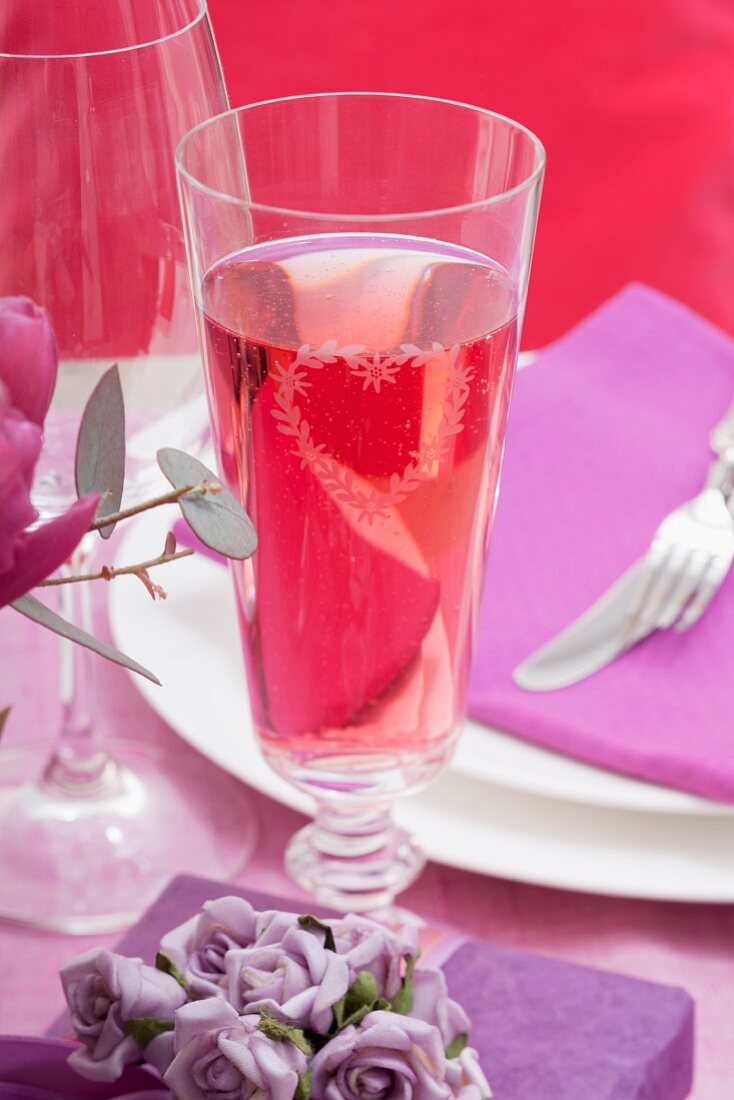 Ein Glas Rose-Sekt auf festlich gedecktem Tisch