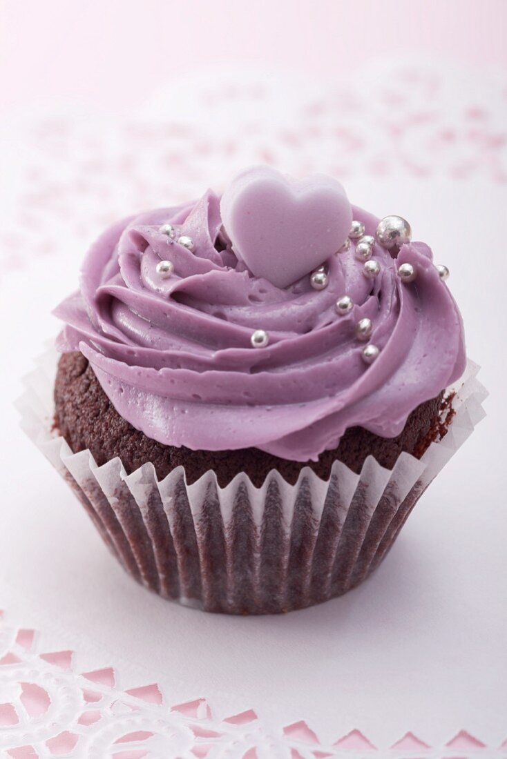 Chocolate cupcake with blackberry icing, silver balls and sugar heart