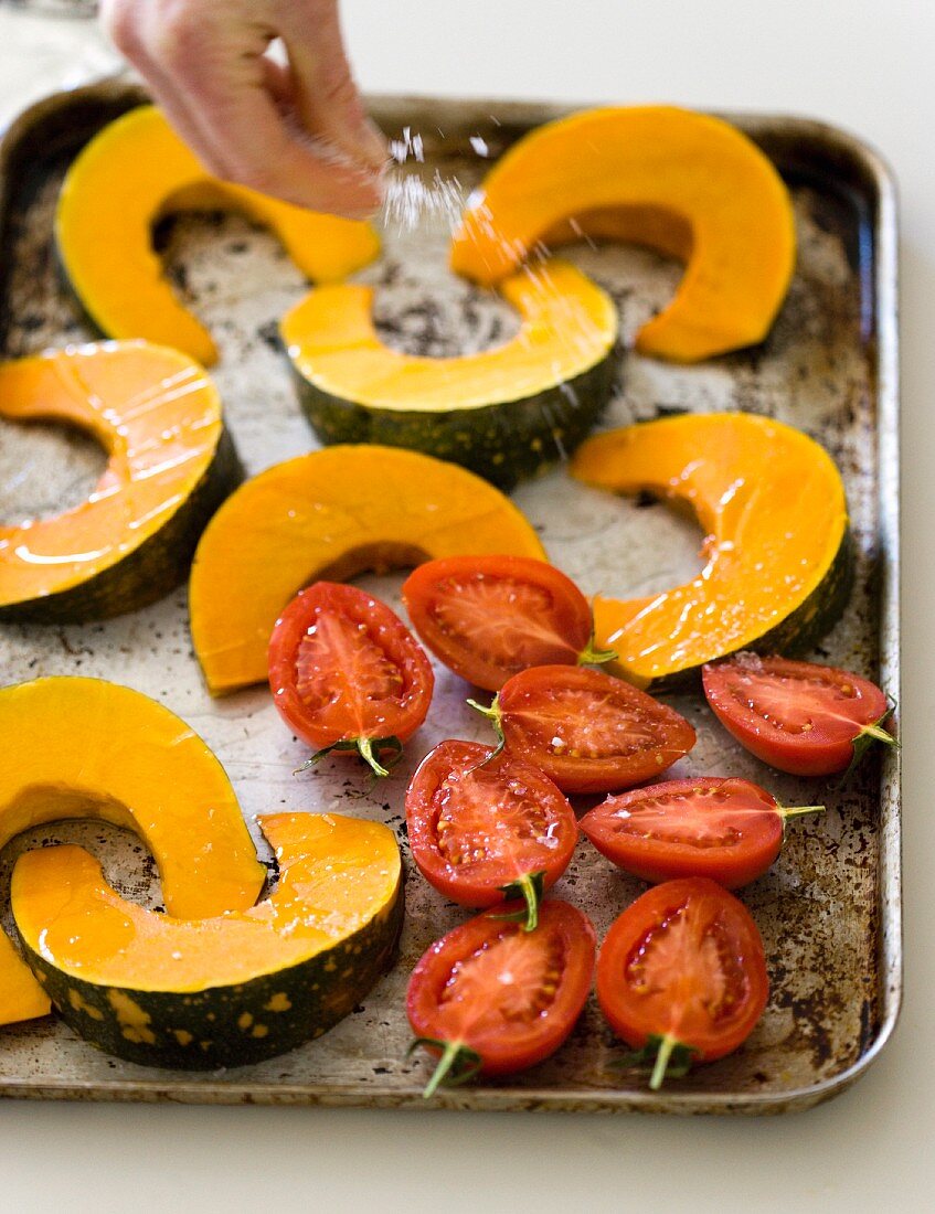 Squash slices and tomatoes being sprinkled with salt