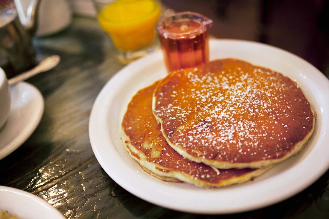 Pancakes, Ahornsirup und Orangensaft zum Frühstück