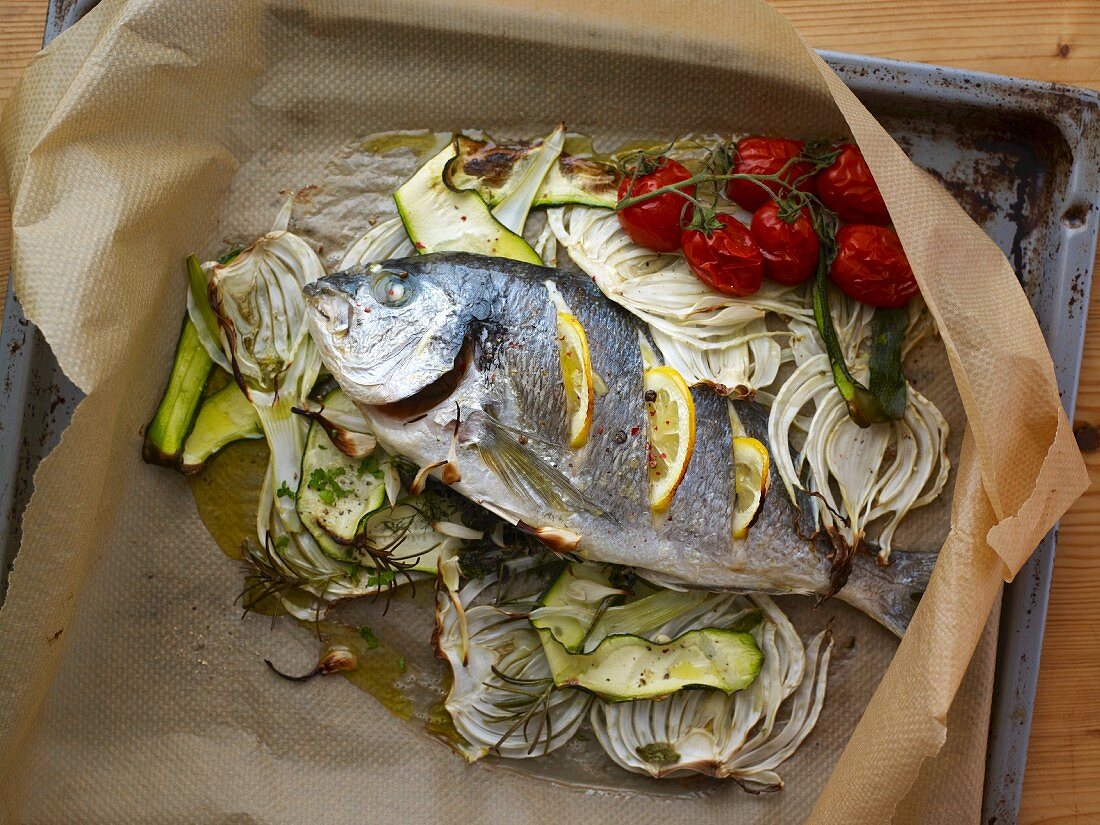 Gilthead with vegetables on parchment paper