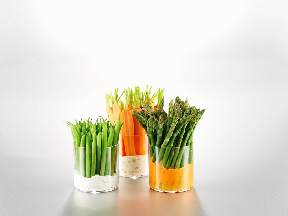 Green beans, carrots and asparagus in glasses with dips
