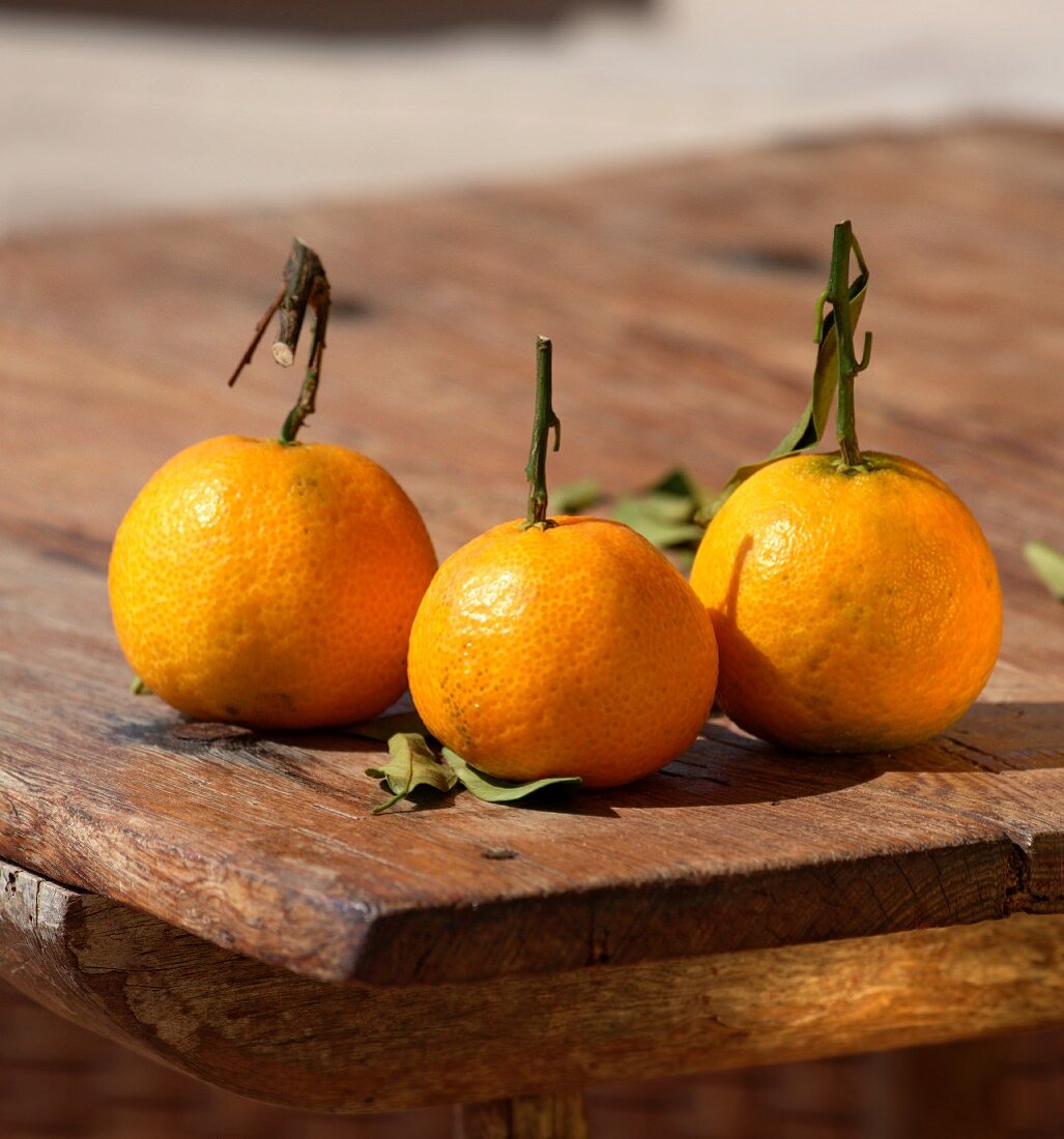 Three tangerines on a wooden table