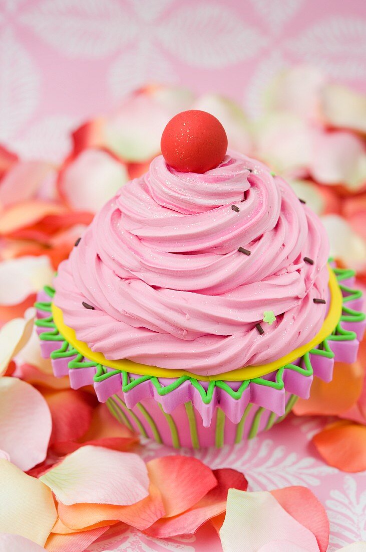 Cupcake mit rosa Buttercreme, umgeben von Rosenblättern