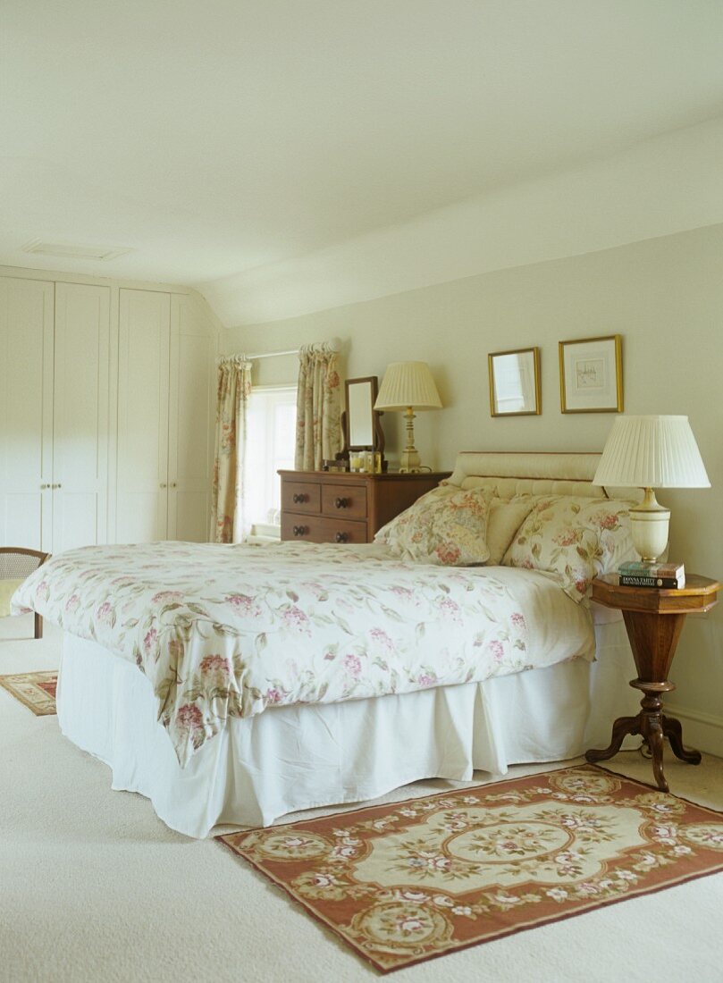 Traditional bedroom with floral throw on bed and Biedermeier-style bedside table