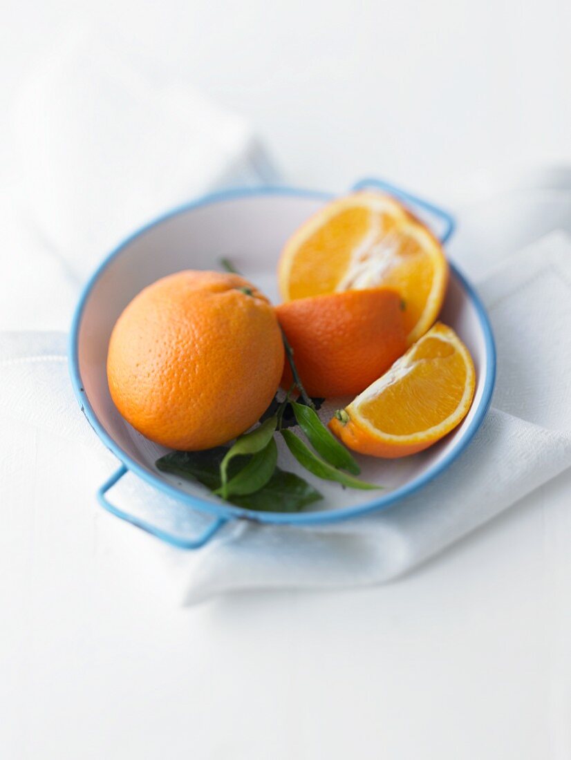 Oranges with leaves in a bowl