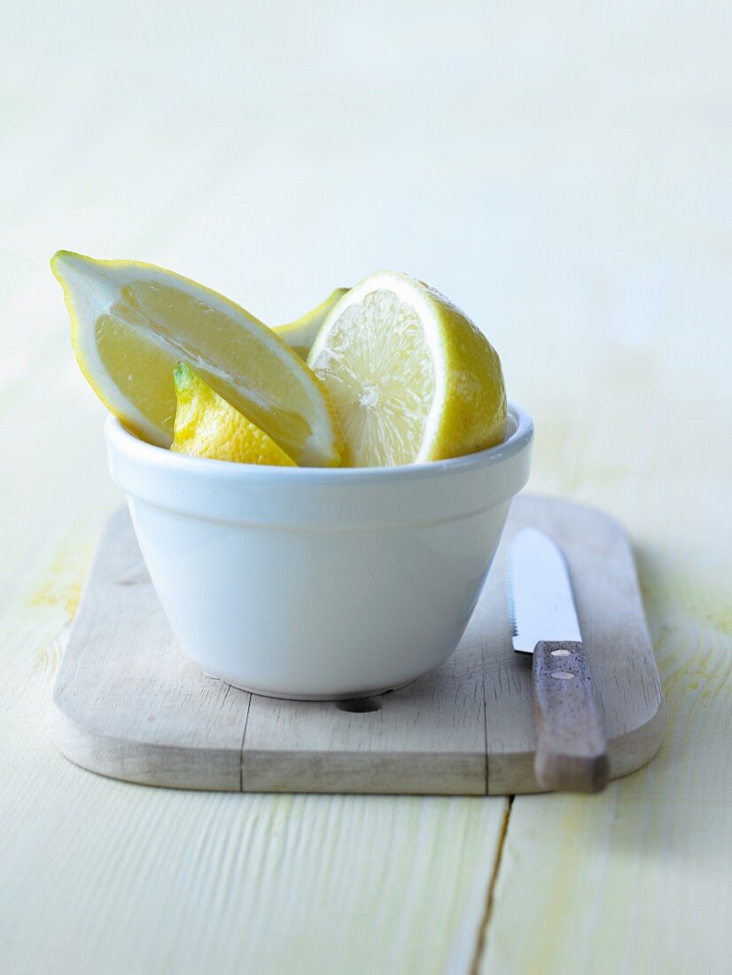 Halbe Zitrone und Zitronenschnitze im Schälchen