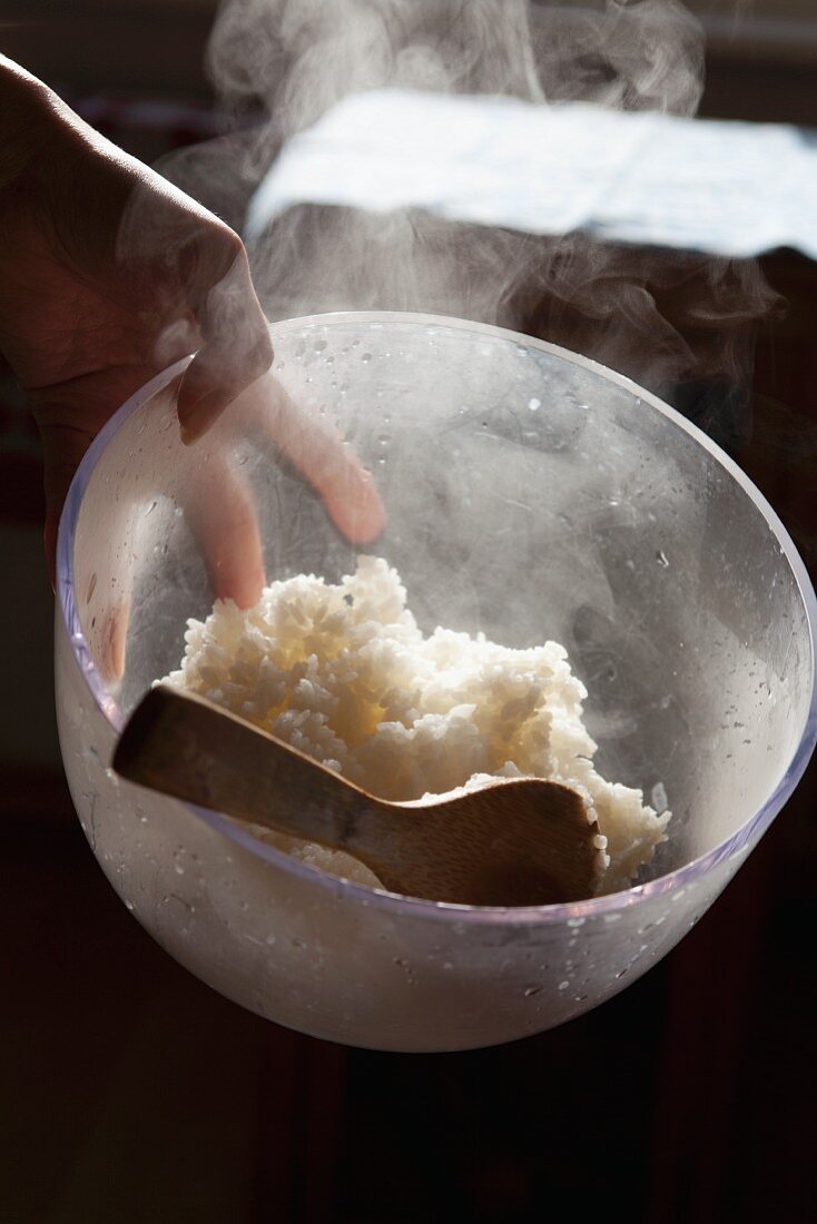 Hand holding a bowl with cooked rice