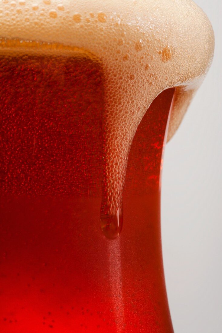 Foam Spilling Over the Edge of a Glass of Amber Ale