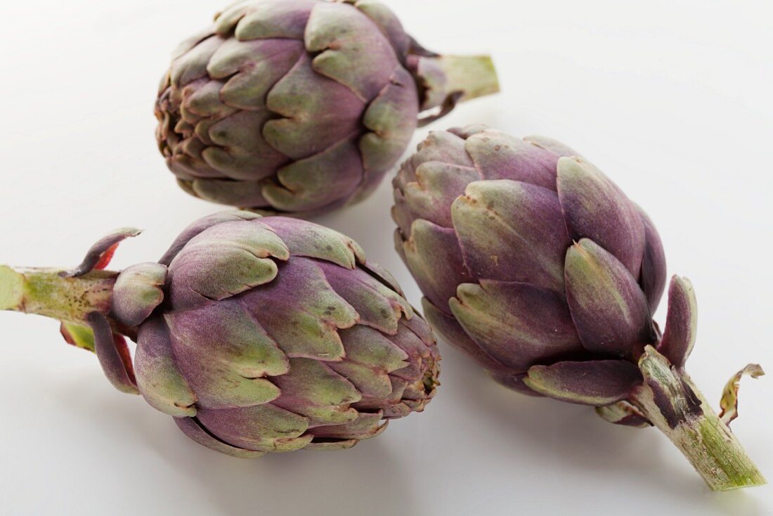 Three, small, purple artichokes