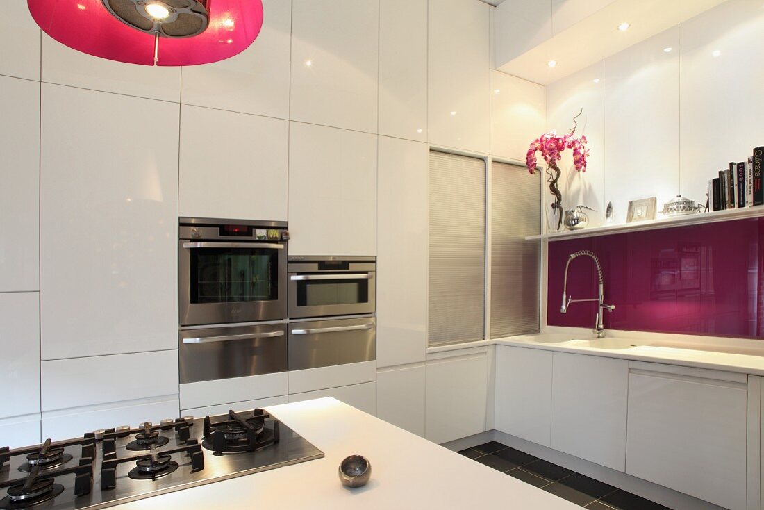 Designer kitchen with gas hob built into kitchen island and white cupboard doors