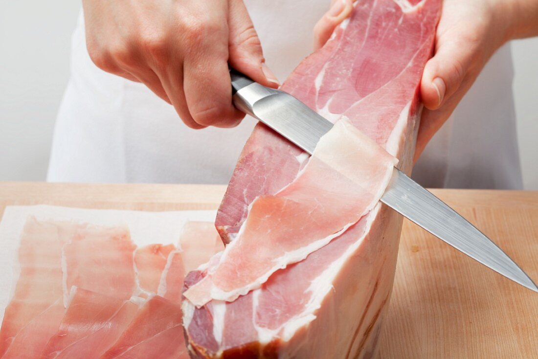 Cutting ham into wafer-thin slices with a knife