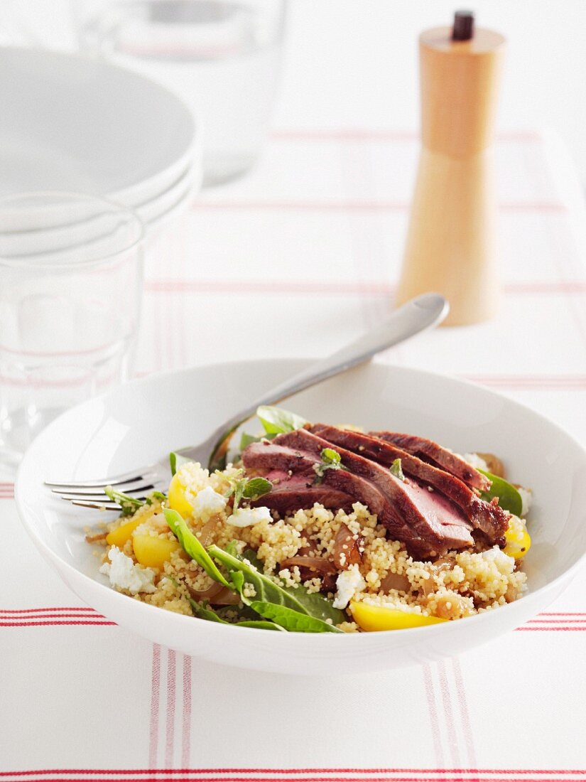 Warm couscous salad with baby spinach and lamb