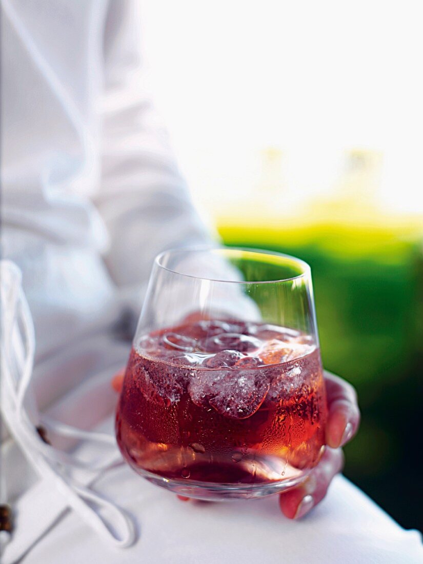 A person holding a glass of verjus (unripened grape juice) with soda