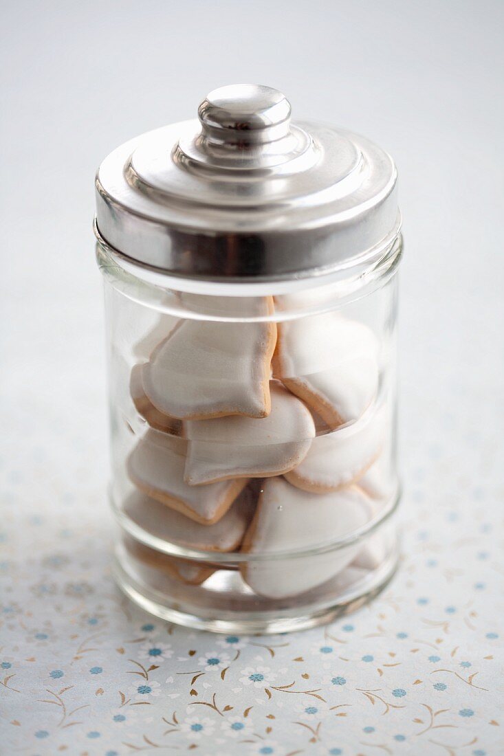 Heart-shaped, iced shortbread biscuits in glass jar