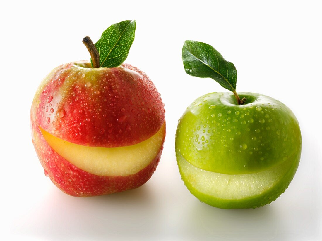 A red and a green apples with a slice taken out of each