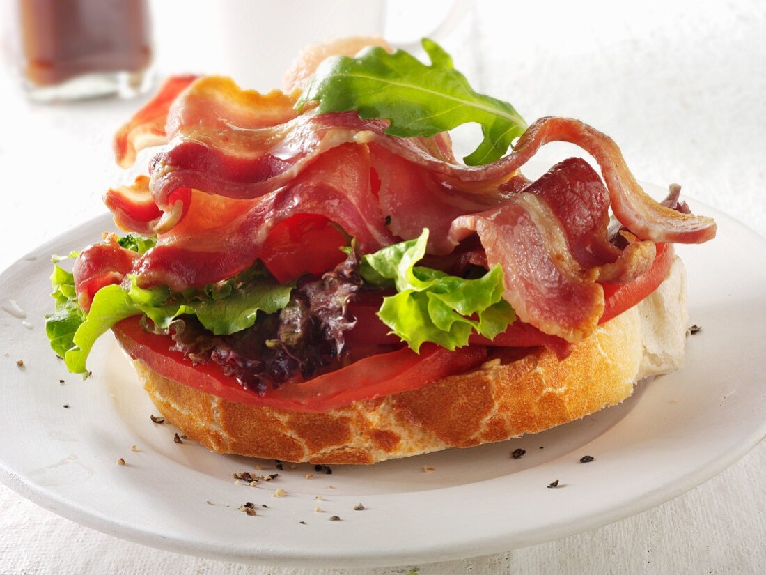 A slice of baguette topped with bacon, lettuce and tomato
