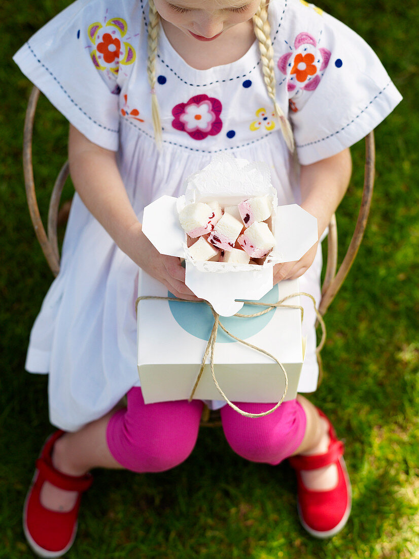Mädchen hält einen Karton Marshmallows