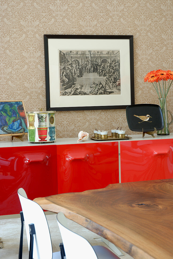 Detail of solid wooden table in front of sideboard with red lacquer doors