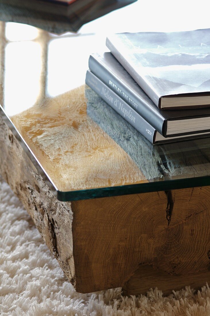 Stack of books on low table made of glass top on wooden block