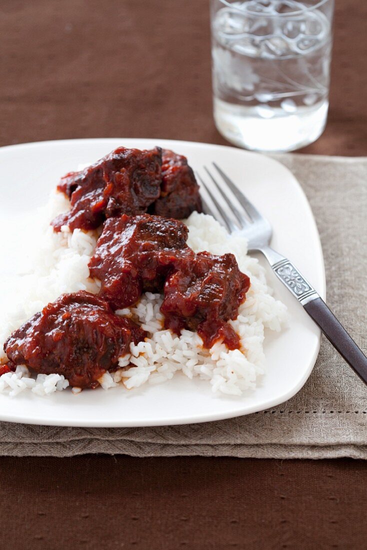 Barbecue Steak Tips on a Bed of Rice; Glass of Water