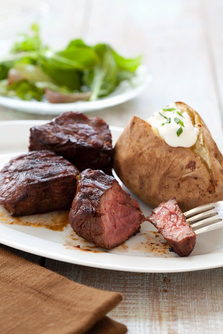 Sirloin Steak Tips with a Baked Potato; Piece of Steak on Fork