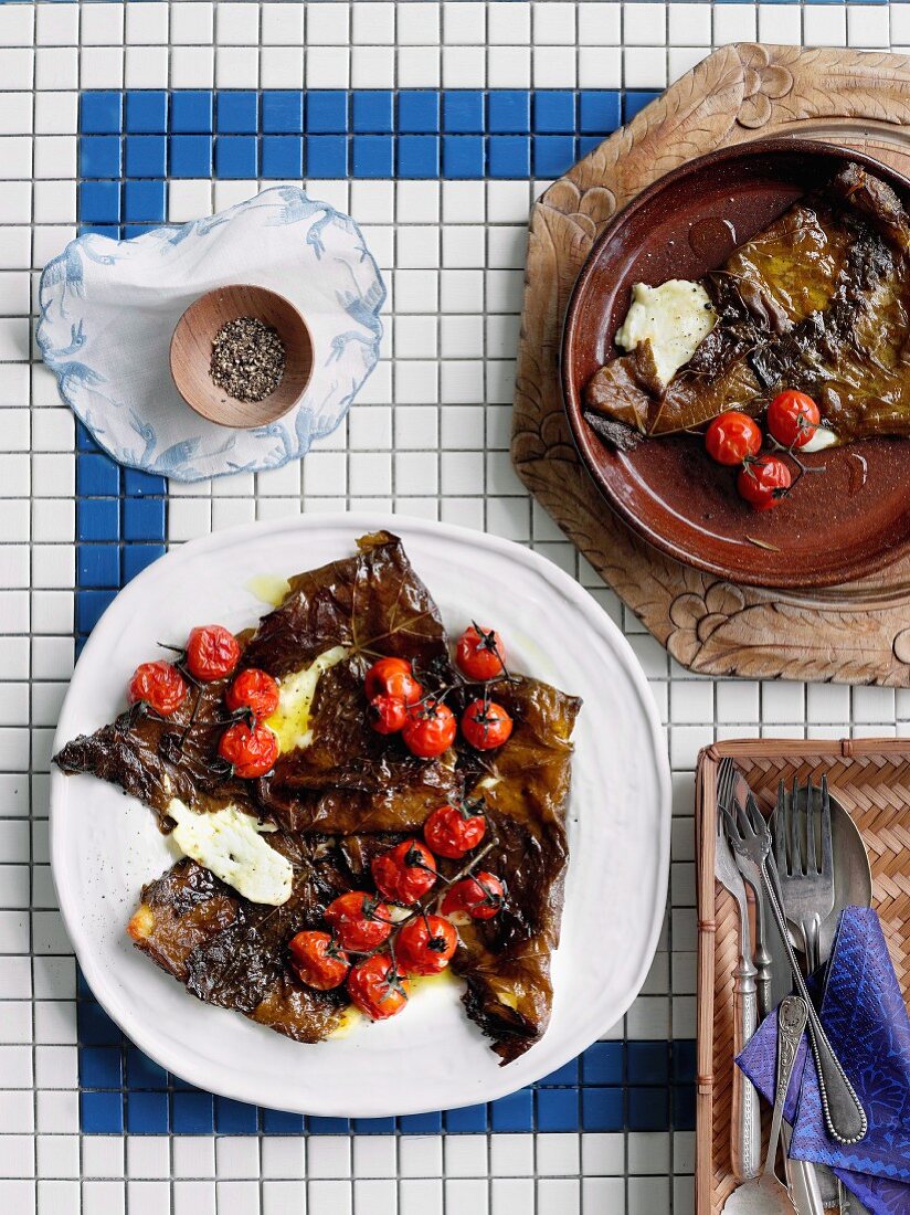 Kefalograviera (Greek cheese) baked in grape leaves and cocktail tomatoes