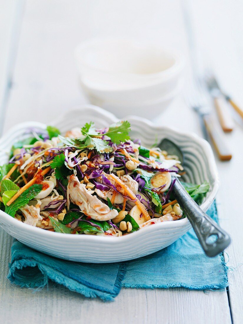 Asian chicken salad with red cabbage, quail eggs and peanuts