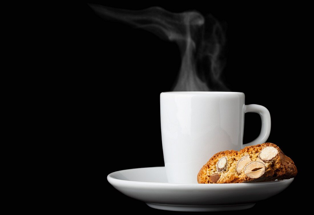 Biscotti (Italian almond biscuits) and a cup of espresso against a black background