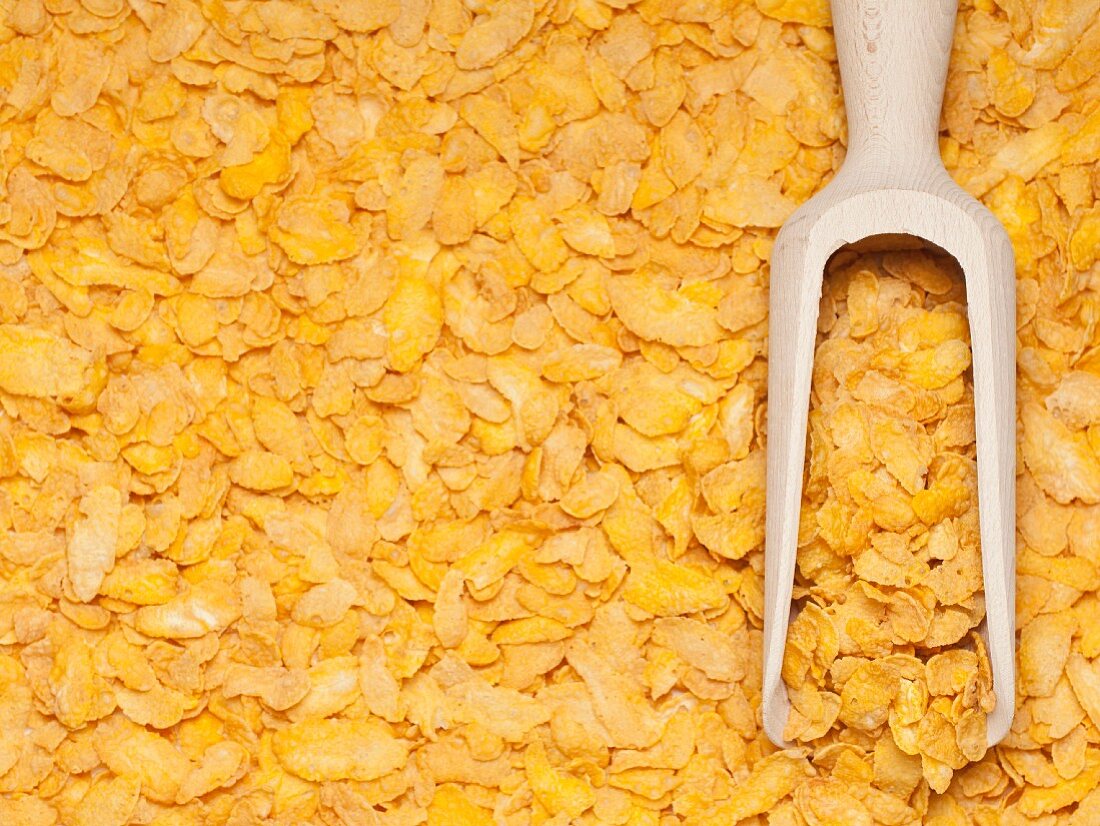 Wooden scoop of cornflakes on a background of cornflakes