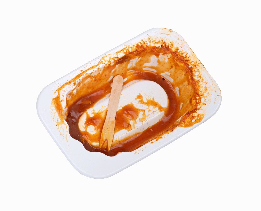 Empty container with currywurst remains in it
