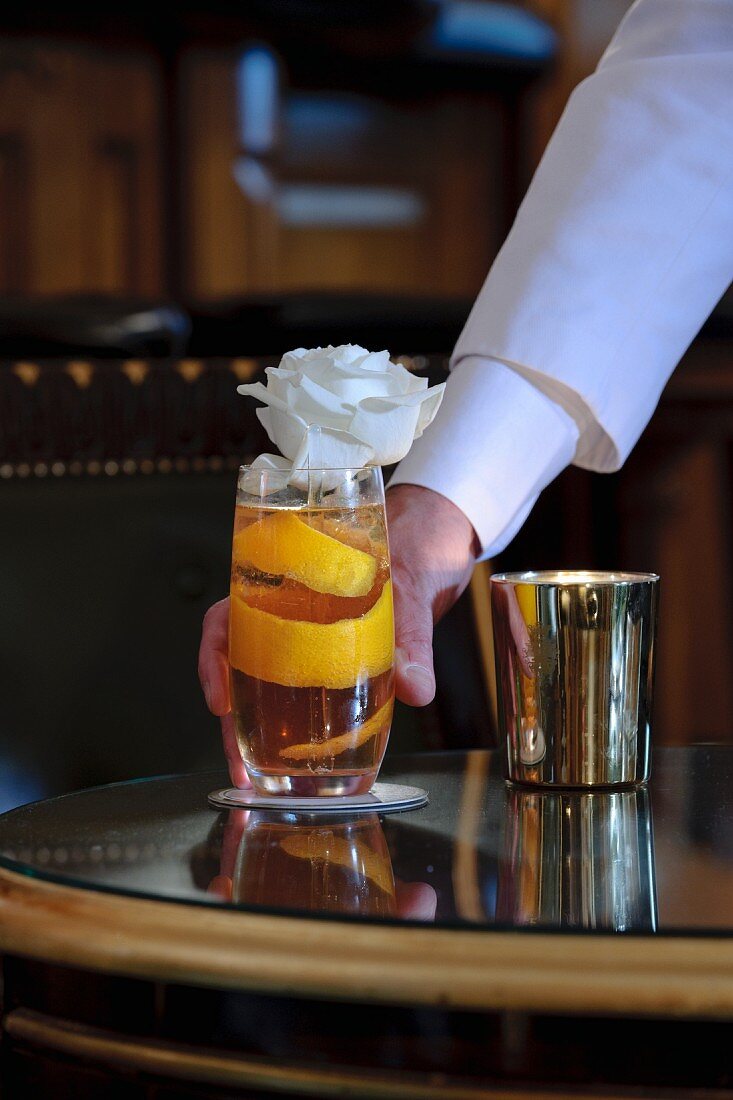 Cocktail mit Orangenschale und Blumendeko