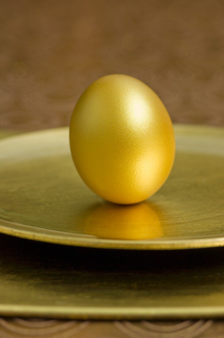 Goldenes Osterei auf goldenem Teller