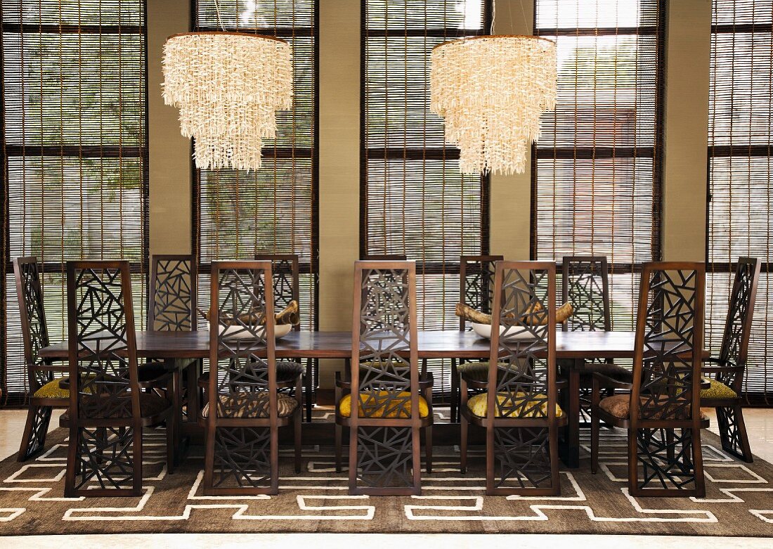 Striking chairs with pierced backs at a long table with modern chandeliers