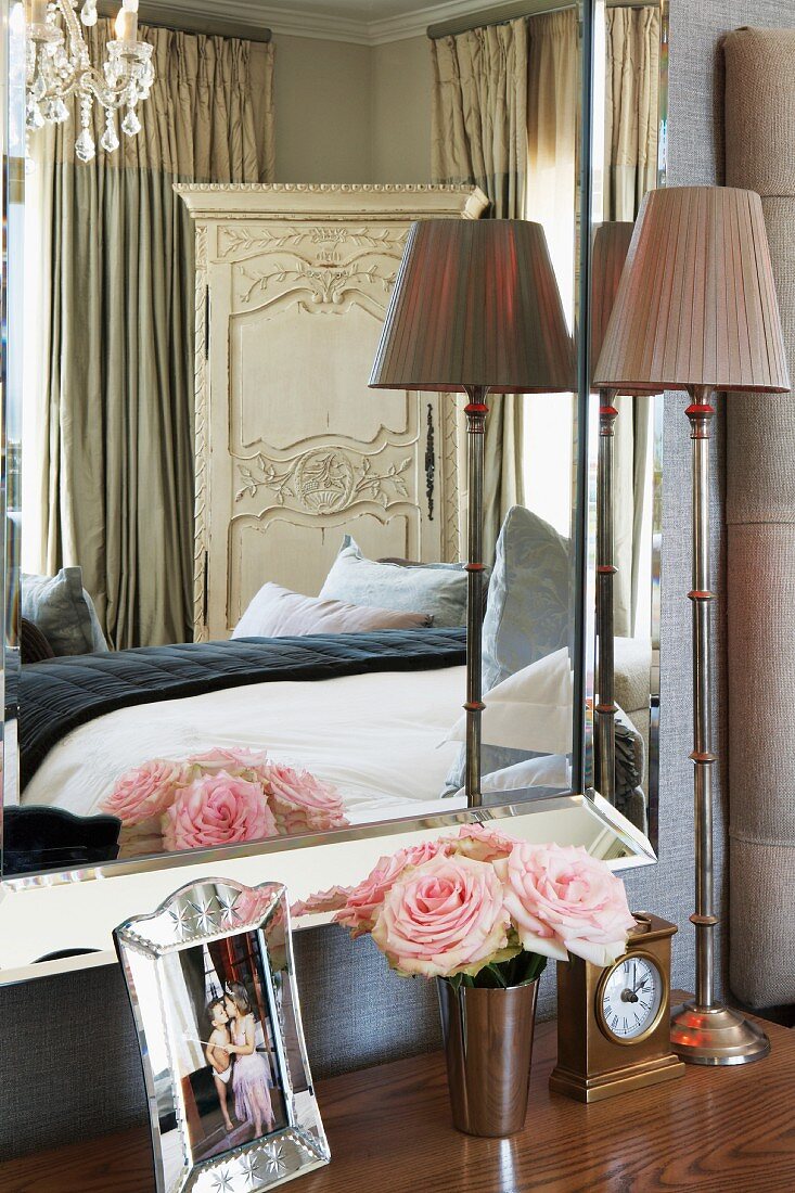 Bedroom mirror reflecting the double bed and an antique cupboard in the corner of the room