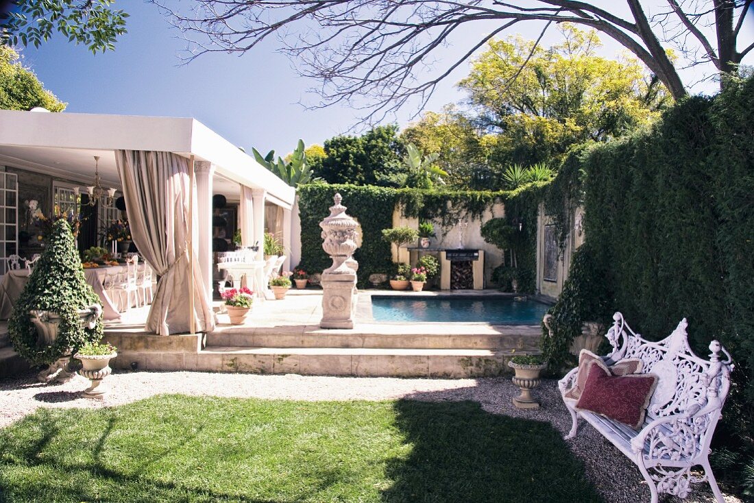 Garten mit antik griechischen Pflanzengefässen vor Pool und Haus mit überdachter Terrasse