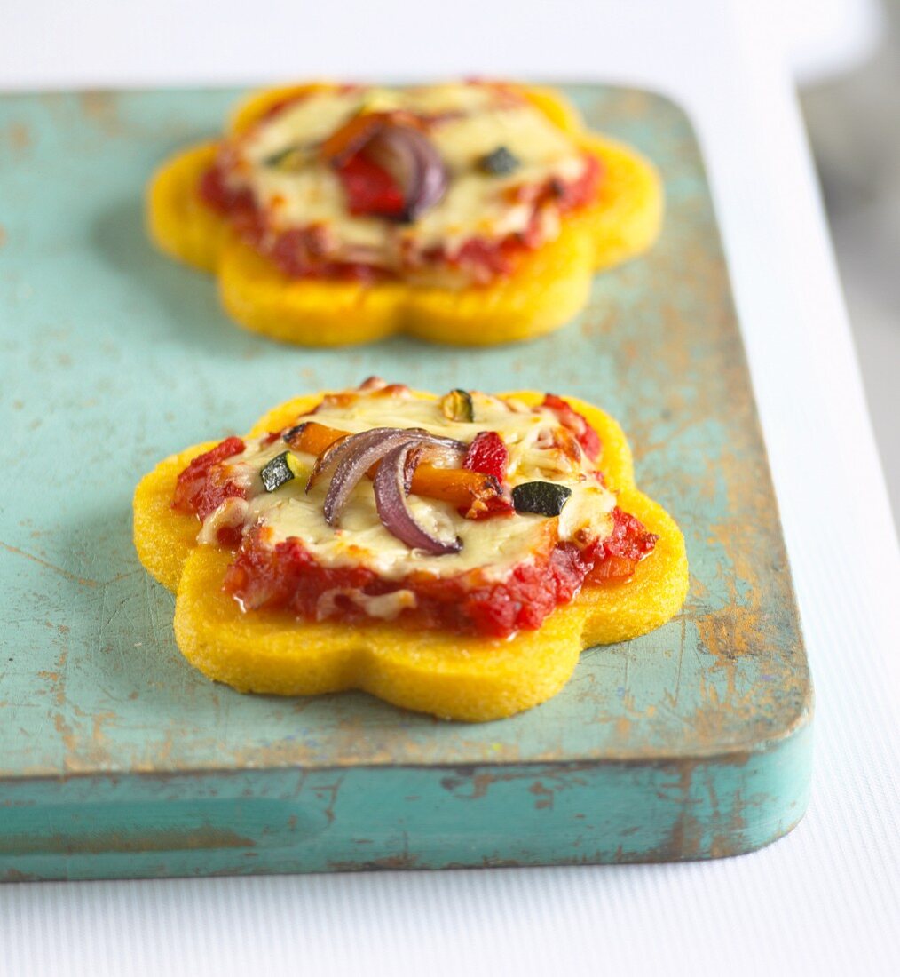 Mini polenta pizzas topped with tomatoes, cheese and onions