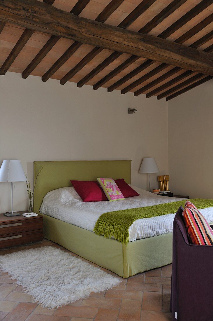 Modern bedroom below rustic ceiling in renovated country house