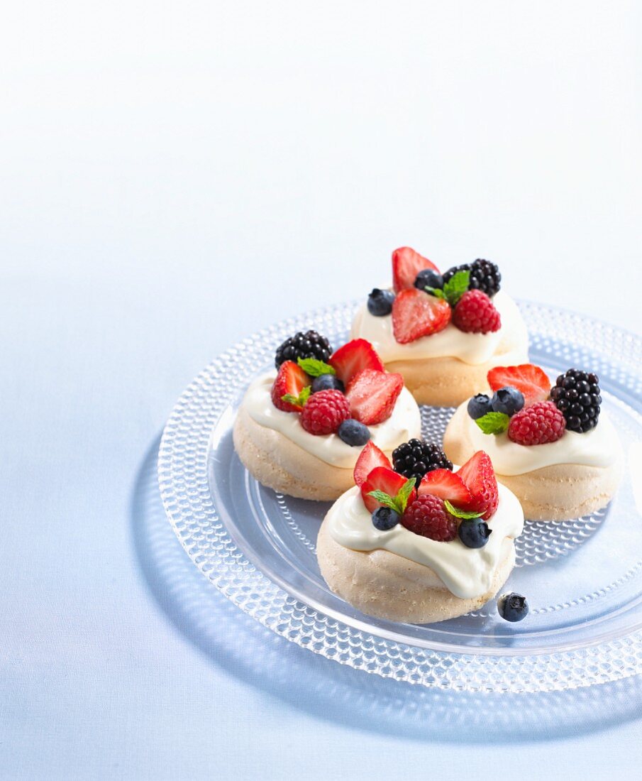 Meringue nests with berries on a glass plate