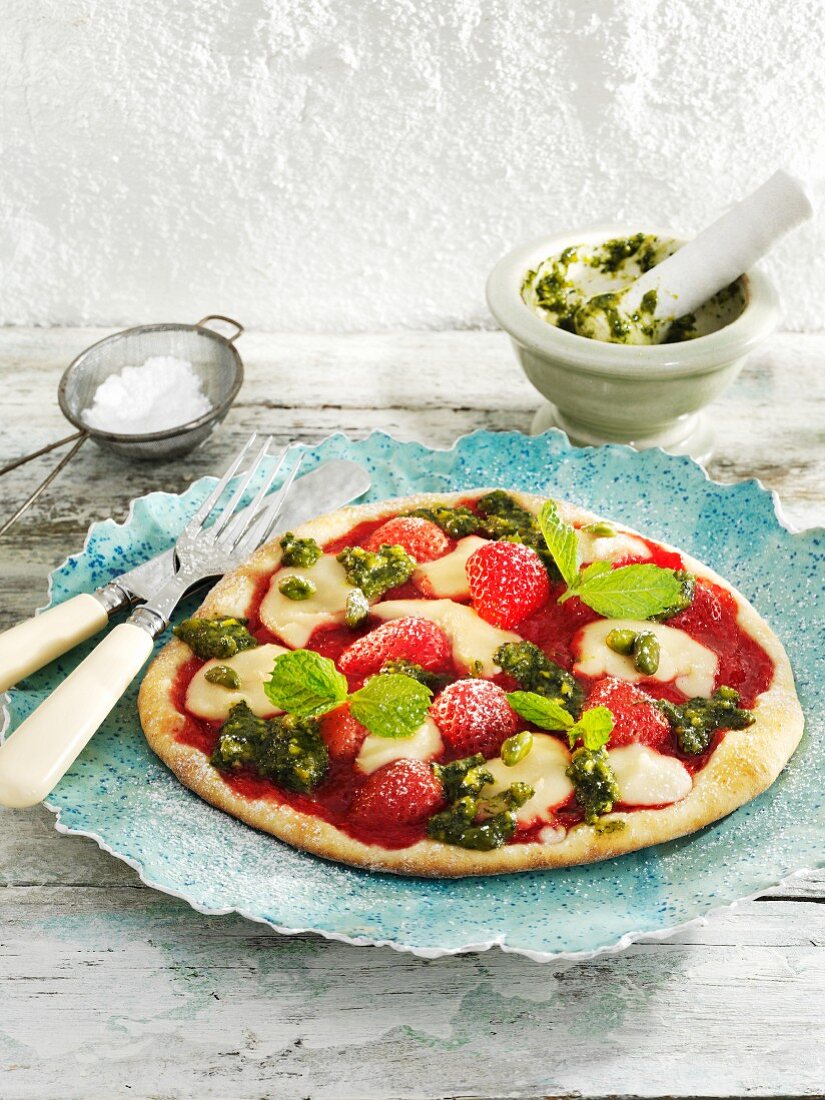 A sweet pizza topped with strawberries, marzipan and pistachio pesto