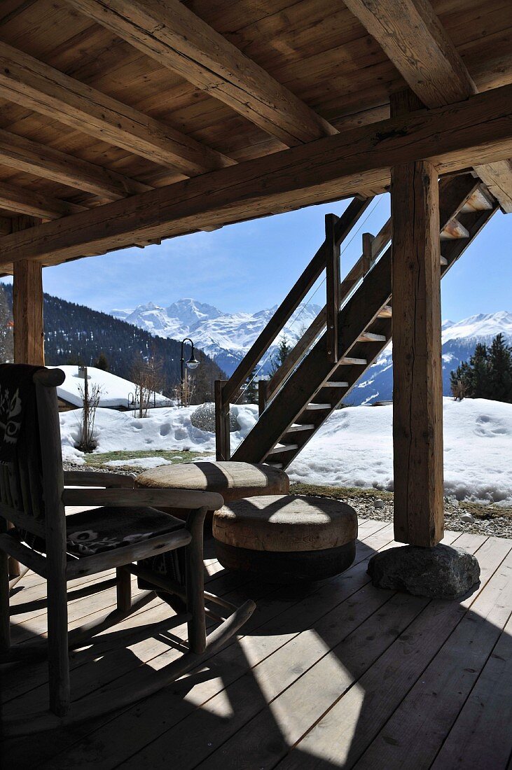 Terrassenplatz vor Holzhütte in verschneiter Berglandschaft