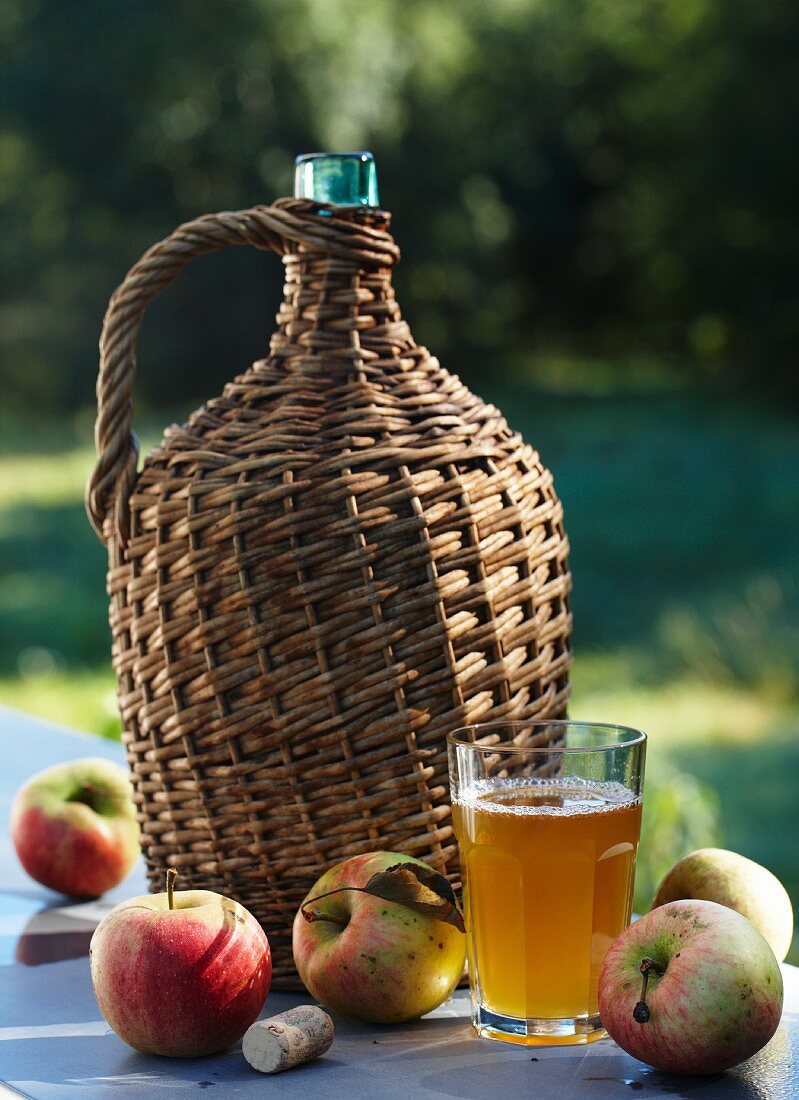 Apfelmost in Korbflasche, Glas mit Apfelsaft & frische Äpfel