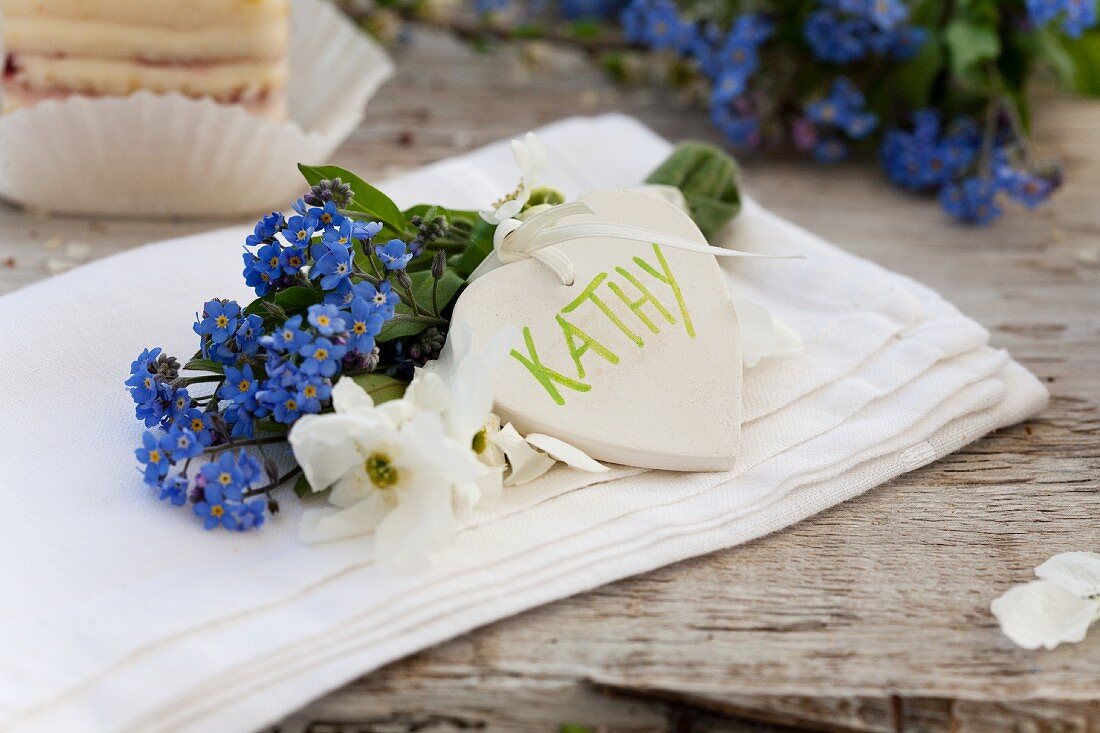 A name written on a heart with a bunch of forget-me-not and garden jasmine