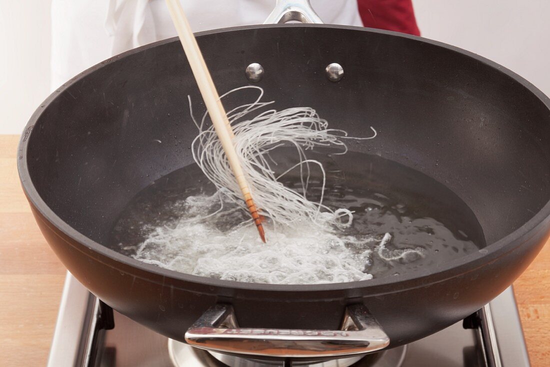 Rice vermicelli being added to hot oil