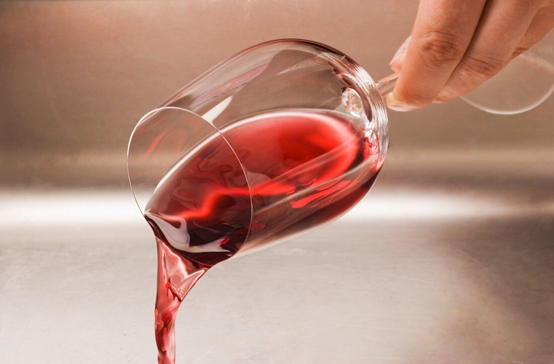 Ein Glas Rotwein ausschütten