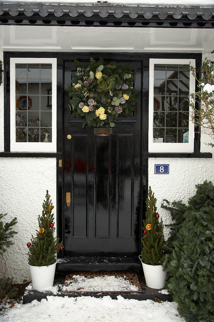 Front door of English country house with Advent wreath and potted conifers decorated for Christmas