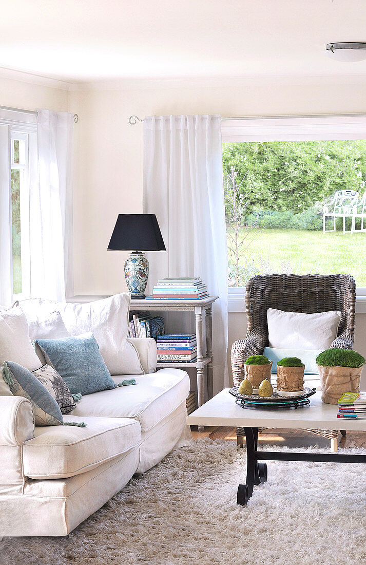 Seating area in country house living room in front of panoramic window with view of garden