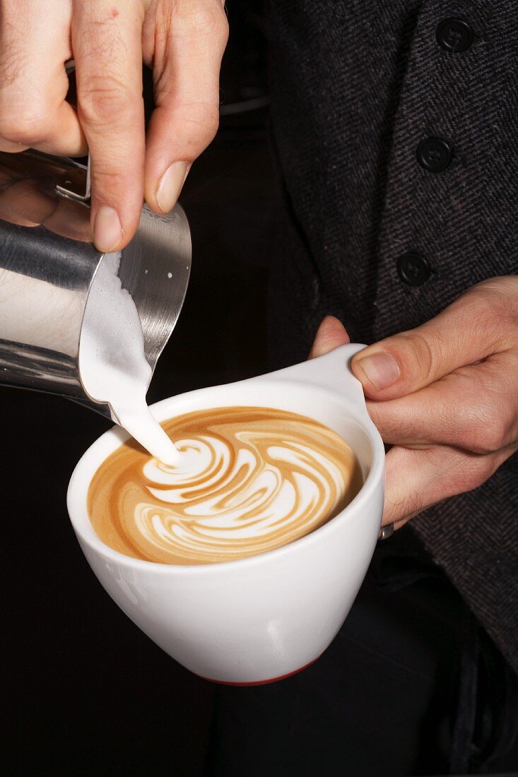 Milchschaum auf einen Espresso gießen